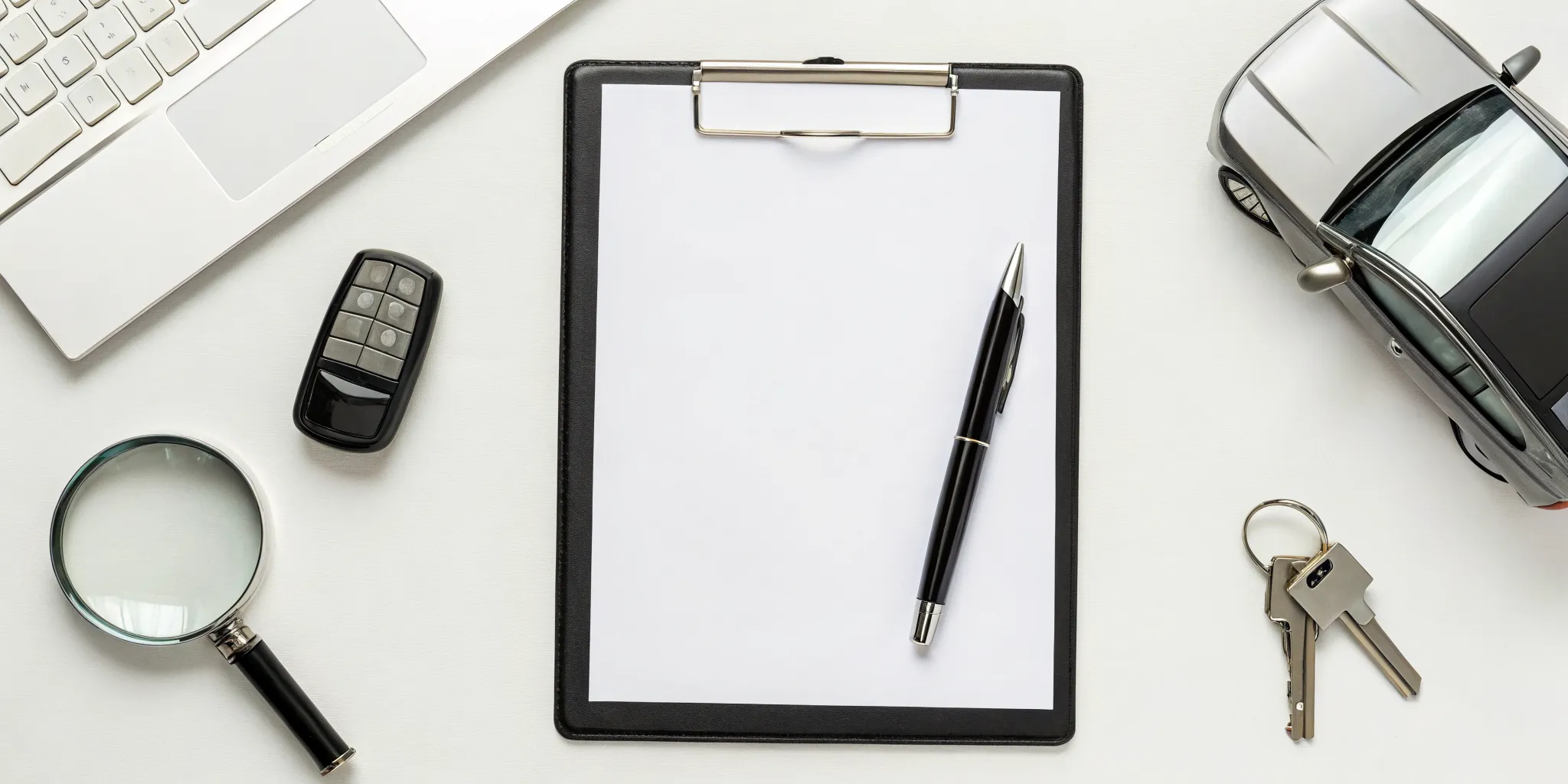 Preparing a diminished value claim letter with a laptop, magnifying glass, and car keys.